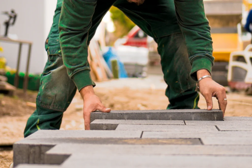 Installer setting concrete pavers by hand