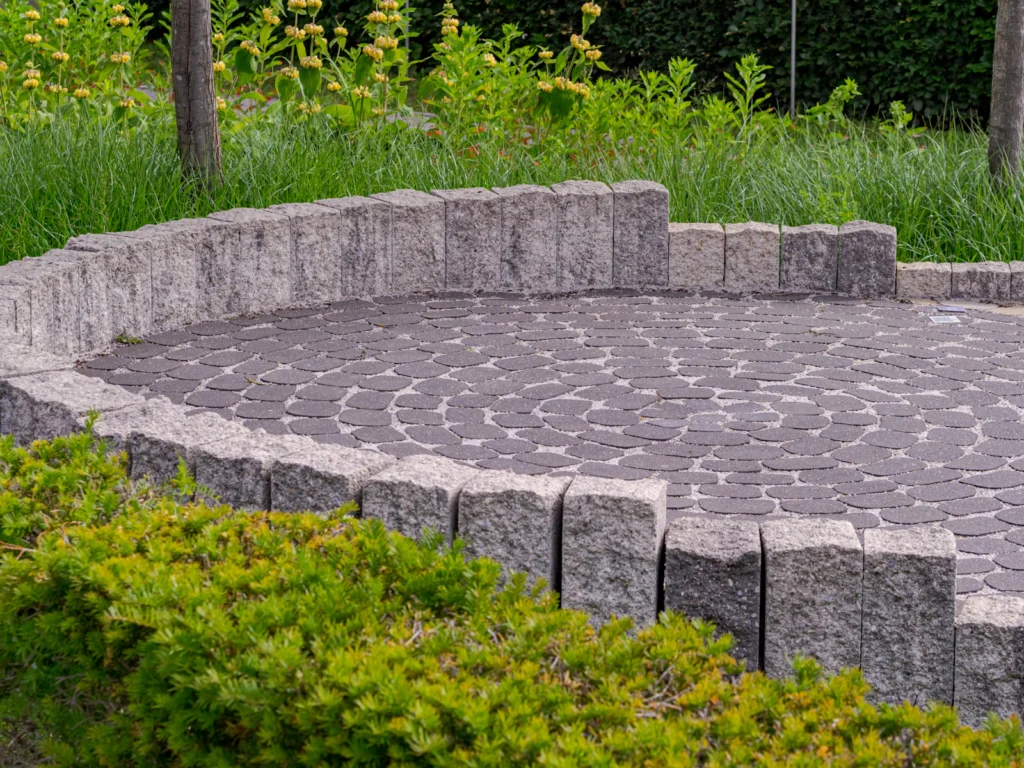 Circular paver patio with a low stone seat wall in a home garden